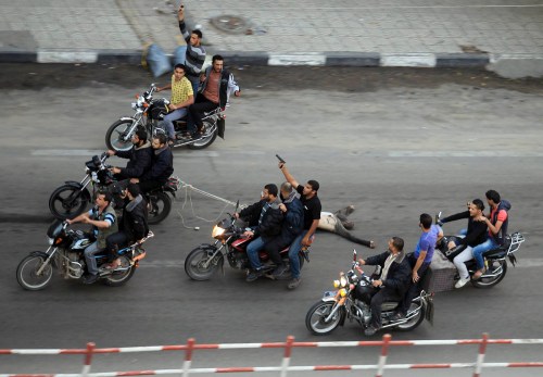 Palestinian gunmen ride motorcycles as they drag the body of a man, who was suspected of working for Israel, in Gaza City